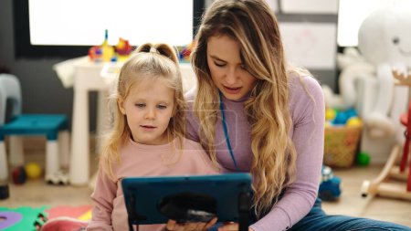 Foto de Mujer y niña teniendo lección usando touchpad en el jardín de infantes - Imagen libre de derechos