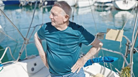 Téléchargez les photos : Homme âgé aux cheveux gris debout avec une expression détendue au bateau - en image libre de droit