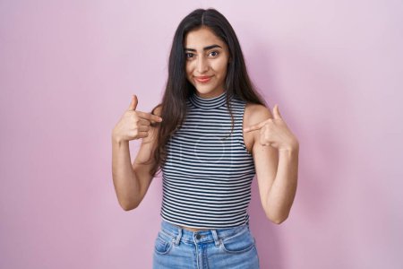 Photo for Young teenager girl wearing casual striped t shirt looking confident with smile on face, pointing oneself with fingers proud and happy. - Royalty Free Image