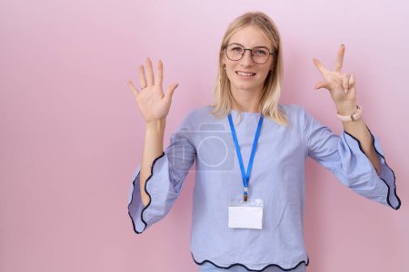Photo for Young caucasian business woman wearing id card showing and pointing up with fingers number eight while smiling confident and happy. - Royalty Free Image