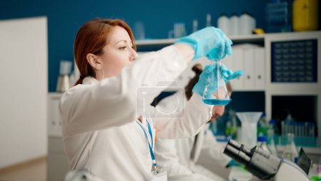 Foto de Hombre y mujer que usan uniforme de cientista usando microscopio en el laboratorio - Imagen libre de derechos