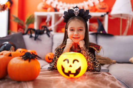 Foto de Adorable chica hispana con disfraz de halloween sonriendo confiada en casa - Imagen libre de derechos