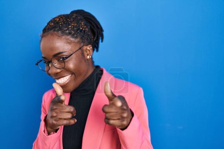 Photo for Beautiful black woman standing over blue background pointing fingers to camera with happy and funny face. good energy and vibes. - Royalty Free Image
