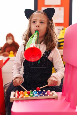Téléchargez les photos : Adorable fille hispanique jouant xylophone et trompette à la maternelle - en image libre de droit