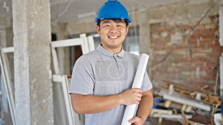 Photo for Architect smiling confident holding blueprints at construction site - Royalty Free Image