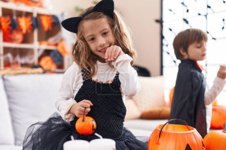 Téléchargez les photos : Adorable garçon et fille ayant fête d'Halloween souriant confiant à la maison - en image libre de droit
