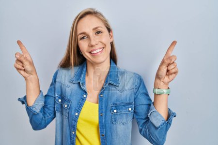 Téléchargez les photos : Jeune femme blonde debout sur fond bleu souriant confiant pointant avec les doigts vers différentes directions. espace de copie pour la publicité - en image libre de droit