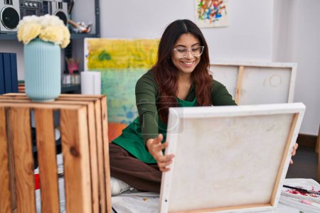 Photo for Young hispanic woman artist looking canvas draw at art studio - Royalty Free Image