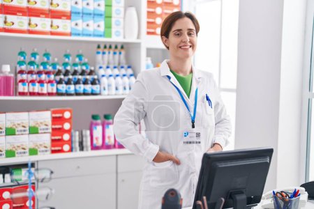 Téléchargez les photos : Young woman pharmacist smiling confident standing at pharmacy - en image libre de droit