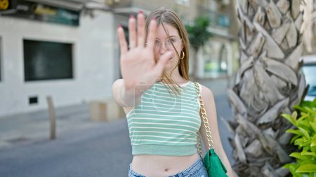 Photo for Young blonde woman doing stop gesture with hand at street - Royalty Free Image