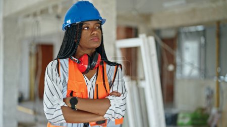 Photo for African american woman builder standing with arms crossed gesture and serious expression at construction site - Royalty Free Image