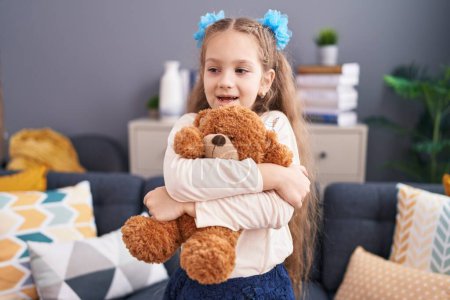 Photo for Adorable caucasian girl smiling confident hugging teddy bear at home - Royalty Free Image