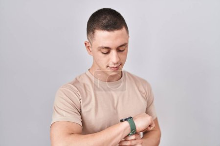 Foto de Young man standing over isolated background checking the time on wrist watch, relaxed and confident - Imagen libre de derechos