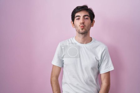 Photo for Young hispanic man standing over pink background looking at the camera blowing a kiss on air being lovely and sexy. love expression. - Royalty Free Image
