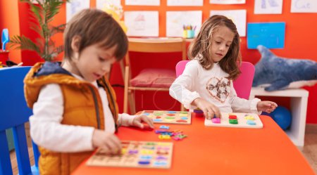 Photo for Adorable boy and girl playing with maths puzzle game sitting on table at kindergarten - Royalty Free Image