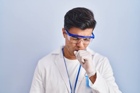 Foto de Hombre hispano trabajando como científico sintiéndose mal y tosiendo como síntoma de resfriado o bronquitis. concepto de atención sanitaria. - Imagen libre de derechos