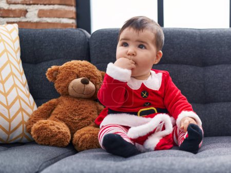Photo for Adorable hispanic baby wearing christmas costume sitting on sofa at home - Royalty Free Image