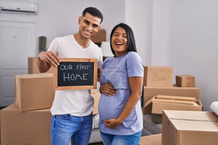Photo for Young hispanic couple expecting a baby moving to a new home smiling and laughing hard out loud because funny crazy joke. - Royalty Free Image