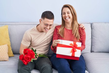 Téléchargez les photos : Homme et femme mère et fils tenant cadeau et fleurs à la maison - en image libre de droit