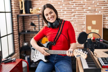 Téléchargez les photos : Young woman artist playing electrical guitar at music studio - en image libre de droit