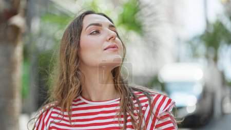 Foto de Mujer rubia joven mirando al cielo con expresión relajada en la calle - Imagen libre de derechos