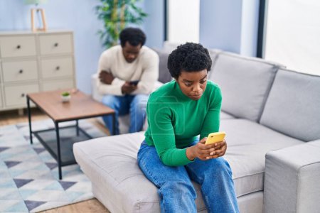 Téléchargez les photos : Couple afro-américain utilisant un smartphone avec des problèmes à la maison - en image libre de droit