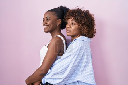 Photo for Two african women standing over pink background looking to side, relax profile pose with natural face and confident smile. - Royalty Free Image