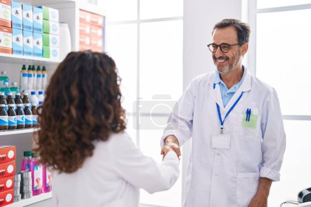 Foto de Farmacéuticos hombres y mujeres sonriendo con confianza dan la mano en la farmacia - Imagen libre de derechos