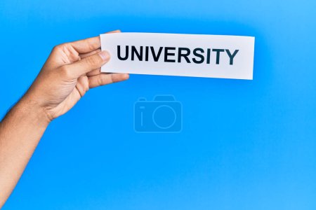 Photo for Hand of caucasian man holding paper with university word over isolated blue background - Royalty Free Image