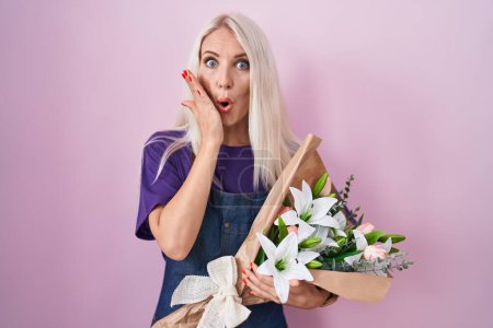 Photo for Caucasian woman holding bouquet of white flowers afraid and shocked, surprise and amazed expression with hands on face - Royalty Free Image