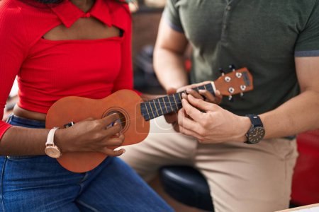 Photo for Man and woman musicians playing ukulele at music studio - Royalty Free Image
