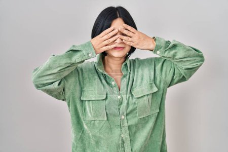 Téléchargez les photos : Jeune femme asiatique debout sur fond blanc couvrant les yeux avec les mains souriantes gaies et drôles. concept aveugle. - en image libre de droit