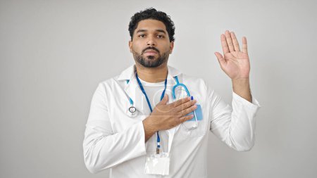 Foto de Médico hombre afroamericano haciendo un juramento con la mano en el pecho sobre fondo blanco aislado - Imagen libre de derechos
