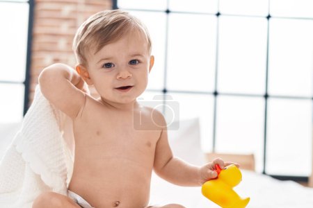 Photo for Adorable caucasian boy holding duck toy sitting on bed at bedroom - Royalty Free Image
