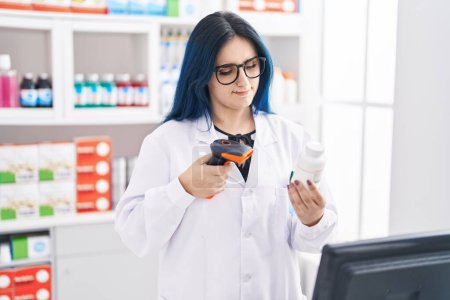Foto de Joven mujer caucásica farmacéutico escaneo píldoras botella en la farmacia - Imagen libre de derechos