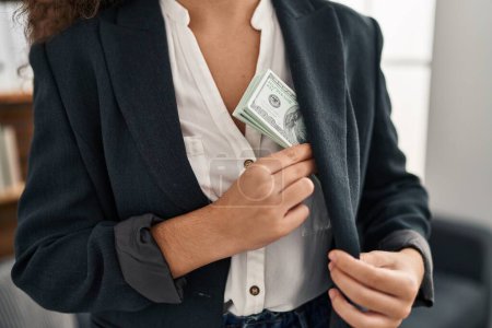 Photo for Young beautiful hispanic woman business worker save dollars on jacket over isolated black background - Royalty Free Image