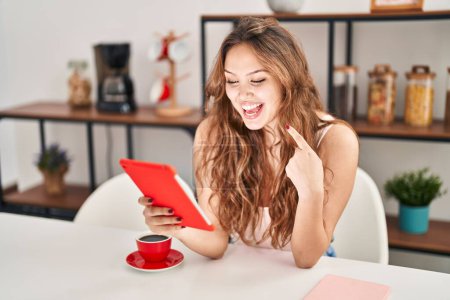 Photo for Young hispanic woman doing video call with tablet smiling happy pointing with hand and finger - Royalty Free Image