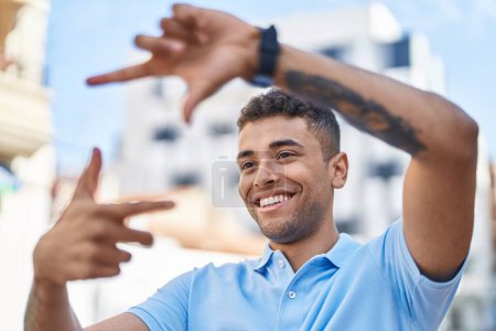 Téléchargez les photos : Afro-américain homme souriant confiant faire geste photo avec les mains à la rue - en image libre de droit
