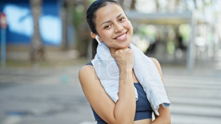 Photo for Young beautiful hispanic woman wearing sportswear using earphones smiling at street - Royalty Free Image