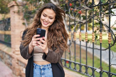 Téléchargez les photos : Jeune belle femme hispanique souriant confiant en utilisant smartphone au parc - en image libre de droit