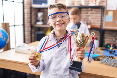 Foto de Adorables estudiantes de niños sosteniendo medalla de oro y copa en el aula de laboratorio - Imagen libre de derechos
