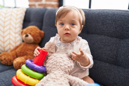 Foto de Adorable bebé caucásico jugando con aros juego sentado en el sofá en casa - Imagen libre de derechos