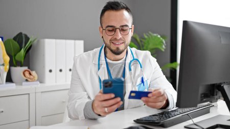 Photo for Hispanic man doctor using smartphone working doing online shopping at the clinic - Royalty Free Image