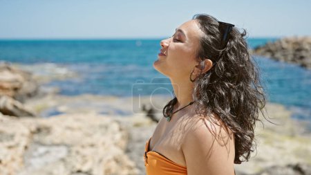 Téléchargez les photos : Young beautiful hispanic woman tourist wearing bikini breathing at beach - en image libre de droit
