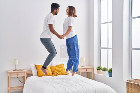 Photo for Man and woman smiling confident jumping on bed at bedroom - Royalty Free Image