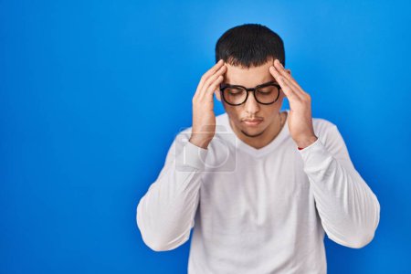 Photo for Young arab man wearing casual white shirt and glasses with hand on head for pain in head because stress. suffering migraine. - Royalty Free Image