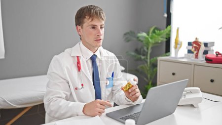 Foto de Joven caucásico médico hombre usando píldoras de prescripción portátil en la clínica - Imagen libre de derechos