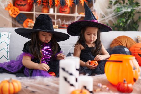 Foto de Adorables chicas gemelas que tienen fiesta de halloween sosteniendo cestas de calabaza en casa - Imagen libre de derechos
