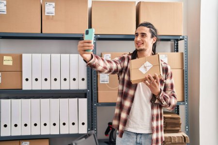 Téléchargez les photos : Jeune homme ecommerce business worker holding package faire selfie par le smartphone au bureau - en image libre de droit