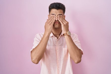 Téléchargez les photos : Jeune homme hispanique debout sur fond rose frottant les yeux pour la fatigue et les maux de tête, somnolent et l'expression fatiguée. problème de vision - en image libre de droit